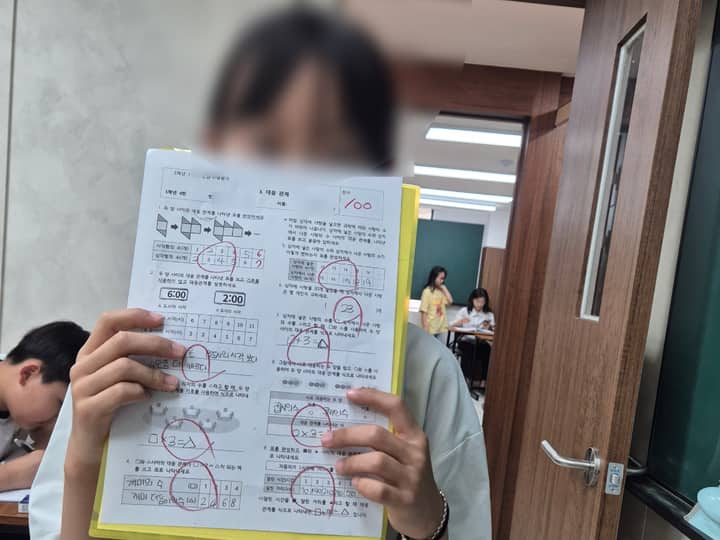 한맥학원 로고 앞에서 수학 100점, 영어 100점 시험지를 든 학생