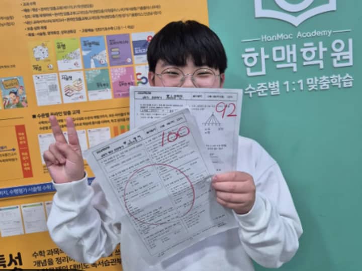 한맥학원 학습 시스템 안내 옆에서 92점, 100점 시험지를 든 학생